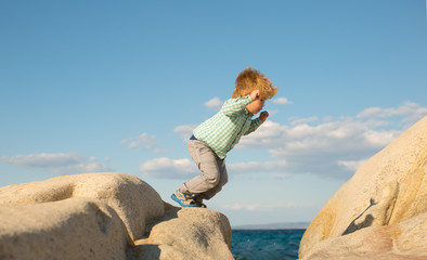 Jumping. Active child. The boy jumps on the stones on the beach.