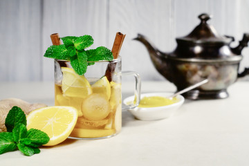 Hot drink with lemon, ginger, honey and cinnamon in a glass cup