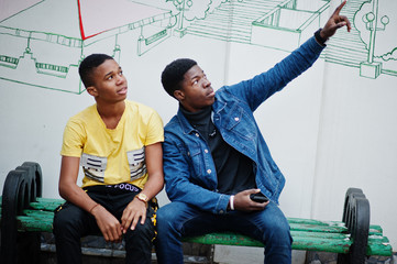 Two african male friends talking together. One of them showing finger on the sky.