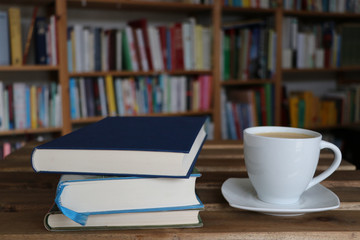 Kaffee, Cappuccino in Tasse mit Buch vor Bücherregal