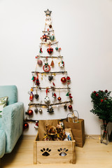 Homemade (Handmade) Christmas Tree at white wall background with decorative lights and new year's decoration