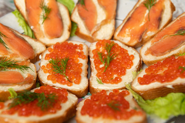 Sandwiches with red caviar and red salted fish toppings - traditional russian snack during new year celebration