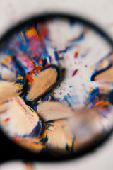 Fototapeta premium Viruta de lápices de colores vista con una lupa con una mirada psicodélica de colores con deformación de la mirada, como se ve con gafas
