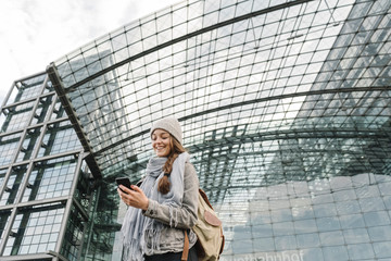 Happy young woman using smartphone at the central station