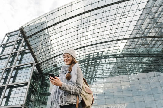 Happy young woman using smartphone at the central station