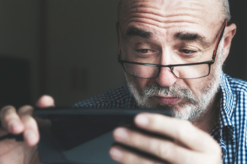 Senior man using smartphone at home