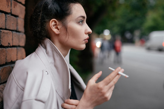 Profile of pensive woman with cigarette outdoors