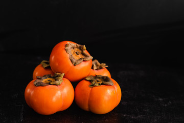 Ripe Fuyu Persimmon Isolated on Dark Background, Copy Space