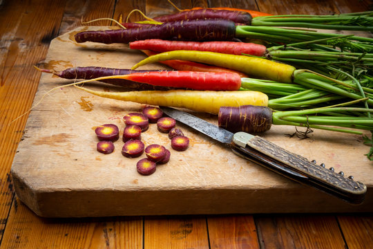 Penknife and fresh colorful carrots lying on cutting board