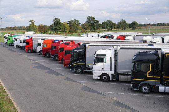 Different types of trucks in a crowded parking lot off the highway.