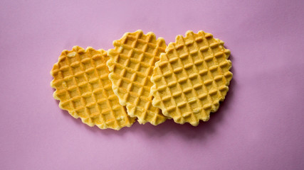 Three oval cookies in a cage on a pink background. View from above.