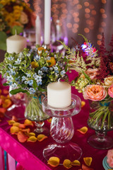 Flowers as a decoration at a wedding. Stunningly beautiful pink peonies, yellow roses and blue flowers in a stuck vase.