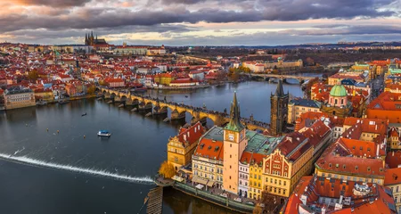Wall murals Prague Prague, Czech Republic - Aerial panoramic drone view of the world famous Charles Bridge (Karluv most) and St. Francis Of Assisi Church with a beautiful winter sunset. St. Vitus Cathedral at background