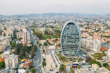 Modern business center with offices in shape of oval or egg in Limassol downtown near embankment, aerial view from drone.