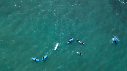 Aerial view of surfer swimming on board near huge blue ocean wave in Porto da Cruz, Madeira island, Portugal