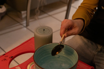 Hand beim Wachsgießen mit erloschner Kerze 