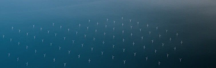 Windmills at the sea. Clean energy made by the wind. Photo in bird perspective. Offshore wind farm.