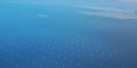 Windmills at the sea. Clean energy made by the wind. Photo in bird perspective. Offshore wind farm.