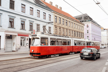 Fototapeta na wymiar Typical red tram on road in Mariahilfer Strasse in Innere Stadt in Old city center in Vienna in Austria. Public transport and Street archtecture in Wien in Europe. Cityscape view. Building landmark.