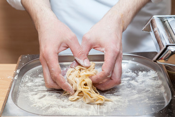 Cook's hands close-up. The process of making a fresh serving of pasta.