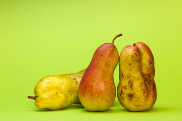 Three ugly pears on a green background. Comparing normal fruits and ugly ones.
