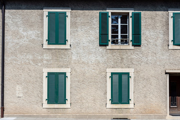 Facade of a stone house with green shutters. Swiss - French border