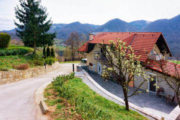 Fototapeta na wymiar Landscape with cottage house in the countryside of Celje old town in Slovenia. Home architecture at the green hill in Slovenija. Alps mountains on the background.