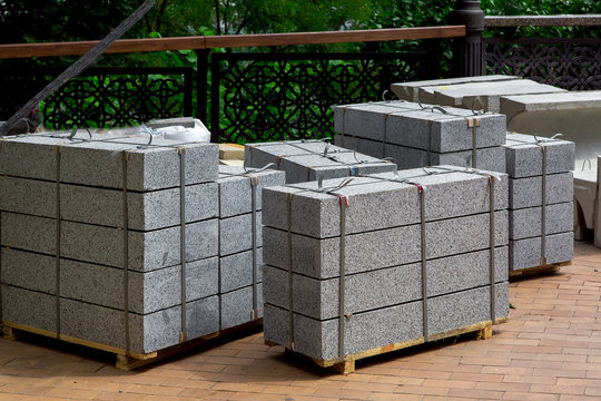gray granite border piled in a pile on a pallet for transportation in the park on stone tile, close up.