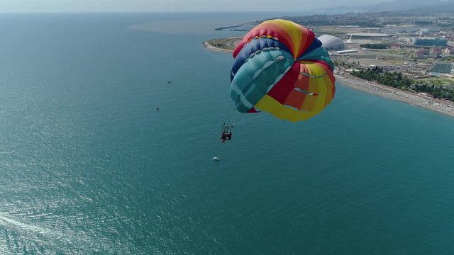 Parasailing colored parachute people tourists fly. Blue water sea ocean. Beach holidays entertainment Sochi Russia famous resort cityscape. Happiness freedom extreme. Summer sunny. Aerial around