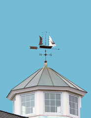 A WEATHER VANE made in a shape of sailing ship and directional points, located on a spire of a buildings tower