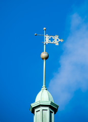 Fototapeta na wymiar A WEATHER VANE with directional points, located on a spire of a buildings tower