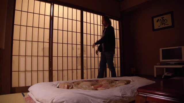 A man walking in a japanese inn and opening sliding doors