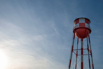 red and white checkered water tower in front of the sky