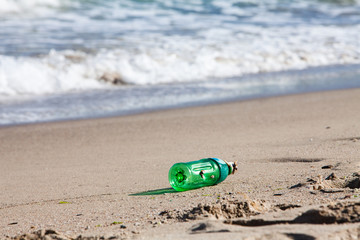 Obraz premium Plastic waste bottle on beach wave sea