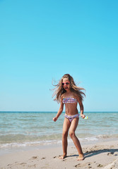 Cute little girl has fun on the beach. Summertime concept.