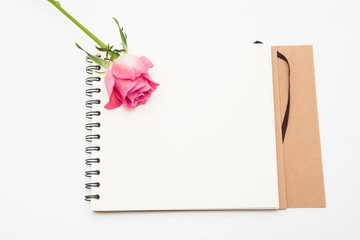 Notepad and pink rose flower on white 