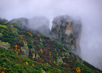 Fototapeta premium Meteora, Greece, winter dramatic landscape with heavy clouds and foggy mountains. Vibrant colorful nature.