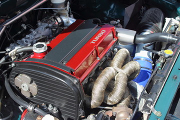Red valve cover turbo motor with intake pipes close up in racing sport car