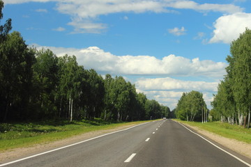 Beautiful Summer empty highway landscape, endless road on Sunny day on trees and cloudy blue sky background