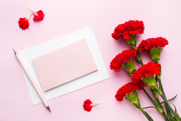 Red-pink objects. Cup of tea, carnation flowers Notepad for text on pastel pink background. Copy space. Top view Flat lay