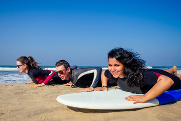 surf instructor and two girls beginner surfers try to stand up on surfboard on lesson in Goa India