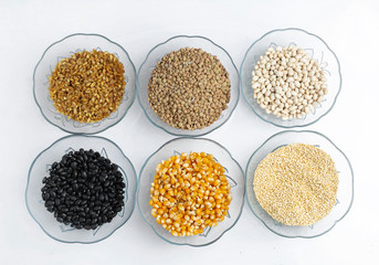 Legumes in glass containers on a table like corn, lentil, rice, oatmeal, beans and quinoa