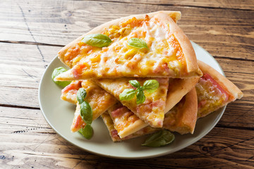 Pieces of homemade pizza on a plate on a wooden table.