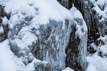 Snow covered rocky cliff face with ice dripping down on the edge