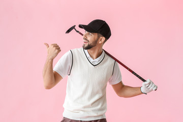 Handsome male golfer pointing at something on color background