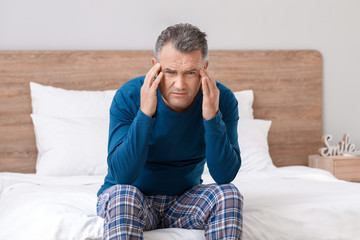 Mature man suffering from head ache in bedroom