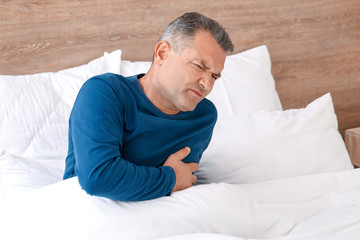 Mature man suffering from heart attack in bedroom