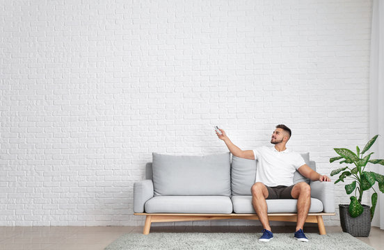 Young Man Switching On Air Conditioner At Home