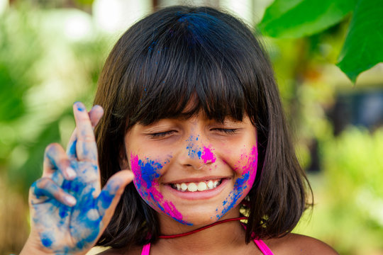 little indian girl painted her face with pink and blue colors