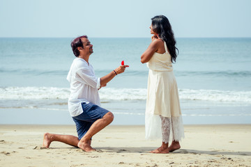 indian male making proposal with engagement ring and roses to his girlfriend at sea beach.Valentine...